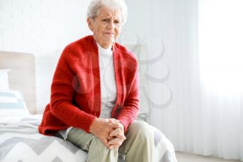 Senior woman suffering from pain in knee at home�