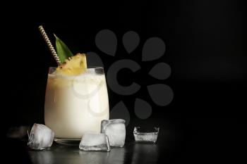 Glass of tasty Pina Colada cocktail on dark background�