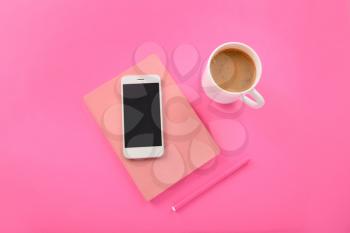 Mobile phone, notebook, pen and cup of coffee on color background�