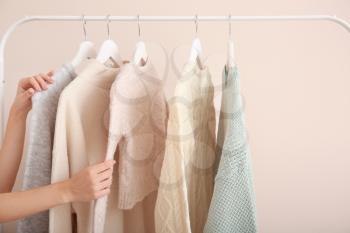 Woman choosing clothes hanging on rack�