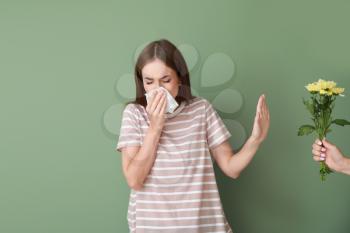 Young woman with allergy refusing to take bouquet on color background�