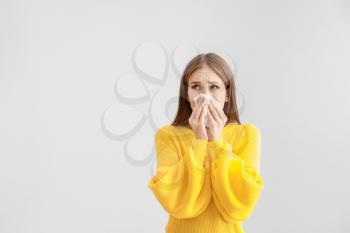 Young woman suffering from allergy on light background�