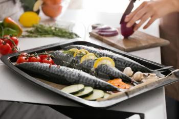 Tray with raw mackerel fish and vegetables on table in kitchen�