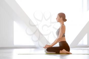 Young woman practicing yoga at home�