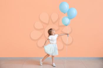Little girl with balloons near color wall�