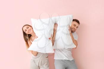Young couple with pillows on color background�