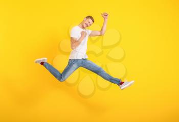 Jumping man in stylish t-shirt on color background�
