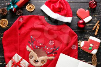 Christmas clothes with gift boxes and cookies on wooden background�