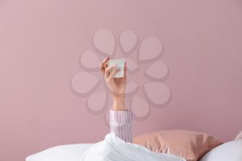 Young woman with cup of coffee lying in bed�