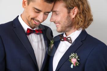 Portrait of happy gay couple on their wedding day against light background�
