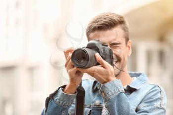 Young male photographer with camera outdoors�