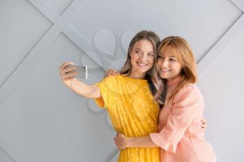 Happy mother and daughter taking selfie at home�