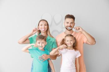 Portrait of family brushing teeth on light background�