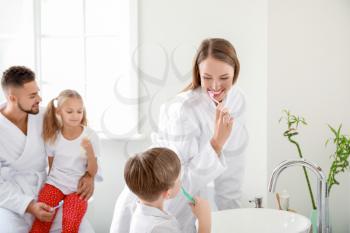Family brushing teeth in bathroom�