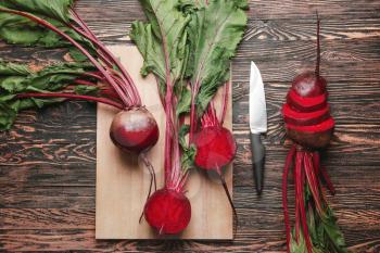 Fresh beets with cutting board and knife on wooden background�