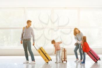 Happy family with luggage in airport�