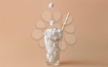 Dropping of sugar cubes into glass on color background�