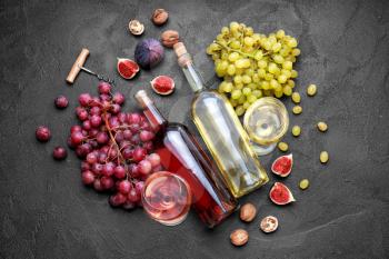 Different tasty wine with grapes on dark background�