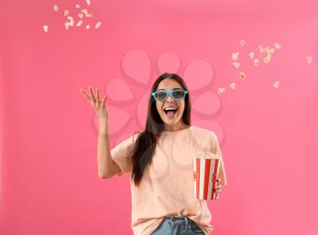 Happy woman throwing popcorn on color background�