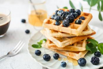Plate with sweet tasty waffles on white table�