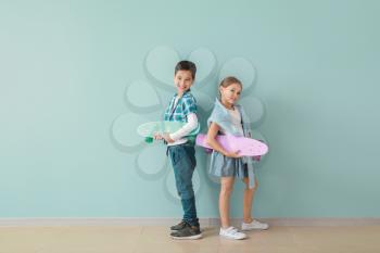 Cute fashionable children with skateboards near color wall�