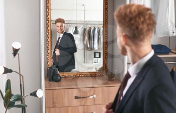 Handsome man trying on stylish clothes in dressing room�