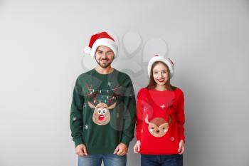 Happy young couple in Christmas clothes on light background�