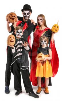 Family in Halloween costumes and with pumpkins on white background�