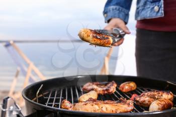 Man cooking meat on barbecue grill outdoors, closeup�