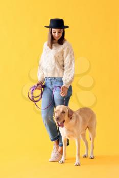 Beautiful young woman with cute dog on color background�