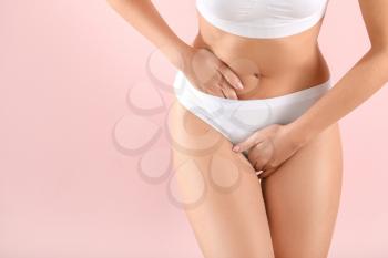 Young woman suffering from abdominal pain on color background. Gynecology concept�