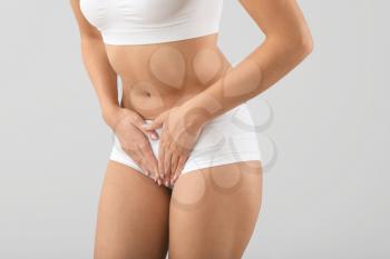 Young woman suffering from abdominal pain on grey background. Gynecology concept�