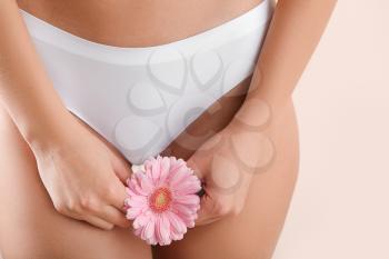 Young woman with flower on light background, closeup. Gynecology concept�