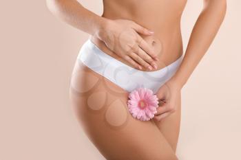 Young woman with flower on light background. Gynecology concept�
