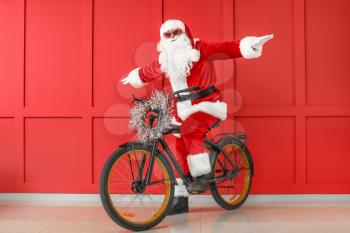 Santa Claus with bicycle on color background�