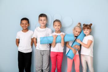 Little children with yoga mats near color wall�
