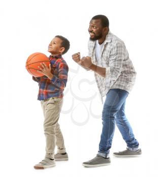 African-American man and his little son playing basketball on white background�