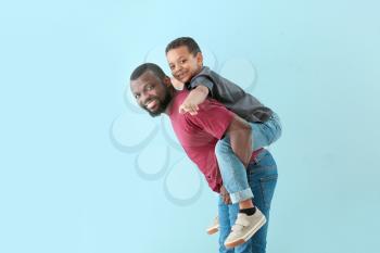 Portrait of African-American man with his little son on color background�