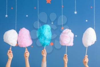 Female hands with different cotton candy on color background�