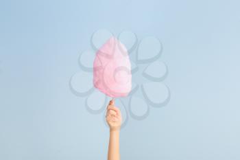 Female hand with tasty cotton candy on light background�