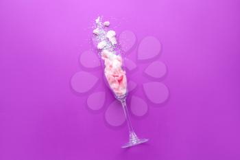 Glass with tasty cotton candy and glitter on color background�
