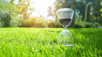 Hourglass on green grass outdoors�
