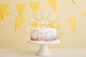 Tasty Birthday cake on table against color background�