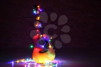 Acoustic guitar with Christmas lights against dark background�