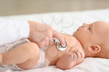 Pediatrician examining cute baby in clinic, closeup�
