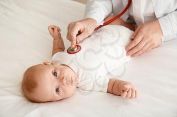 Pediatrician examining cute baby in clinic�