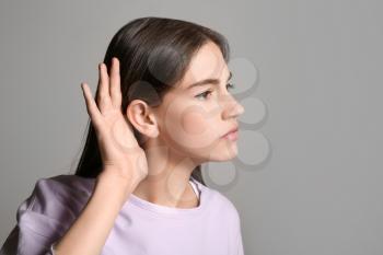 Young woman with hearing problem on grey background�