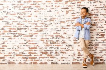 Fashionable African-American boy near brick wall�