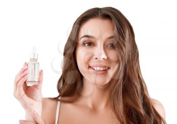 Beautiful young woman with bottle of serum on light background�
