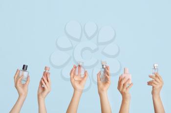 Female hands with different perfume bottles on color background�